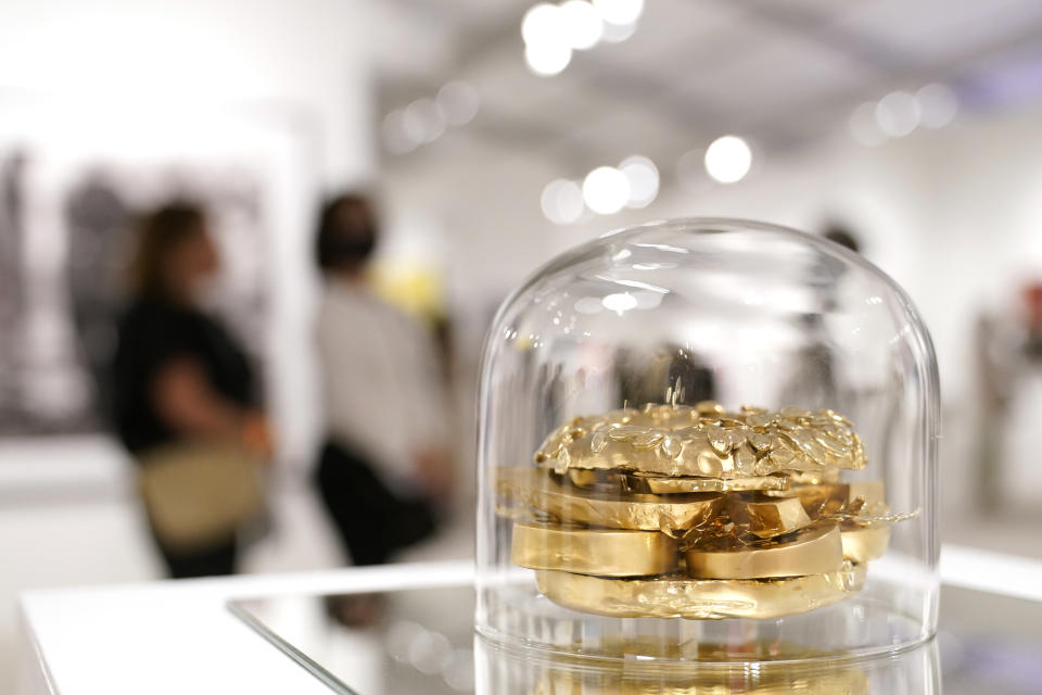 Artwork titled Who Wants to Live Forever by German artist Tim Bengel is displayed by Galerie Rother at Art Miami during Miami Art Week, Wednesday, Dec. 1, 2021, in Miami. Miami Art Week is an annual event centered around the Art Basel Miami Beach fair. The piece depicts avocado on a toasted bagel, is made of 18-karat gold and is selling for $2.9 million dollars. (AP Photo/Lynne Sladky)