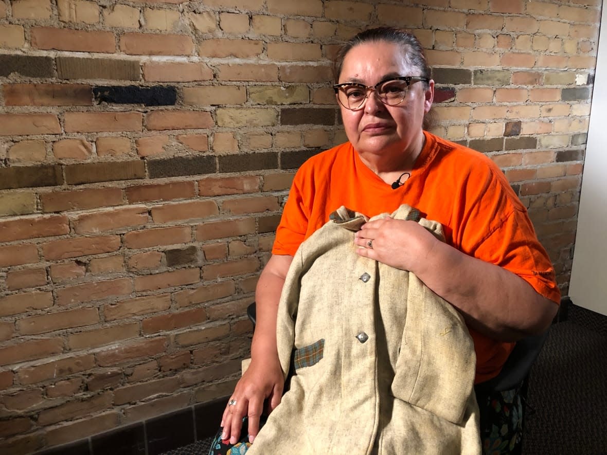 Victoria McIntosh holds the jacket she wore on her first day of school at Fort Alexander residential school. She says she would later be sexually abused there by Father Arthur Masse, who was arrested last week and charged with indecent assault. (Warren Kay/CBC - image credit)