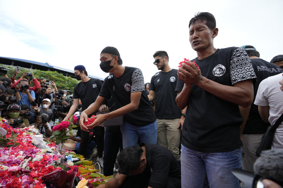 Players and officials of the soccer club Arema FC pray outside the Kanjuruhan Stadium where many fans lost their lives in a stampede Saturday night in Malang, Indonesia, Monday, Oct. 3, 2022. Police firing tear gas at Saturday night's match between host Arema FC of East Java's Malang city and Persebaya Surabaya in an attempt to stop violence triggered a disastrous crush of fans making a panicked, chaotic run for the exits, leaving a large number of people dead, most of them trampled upon or suffocated. (AP Photo/Achmad Ibrahim)