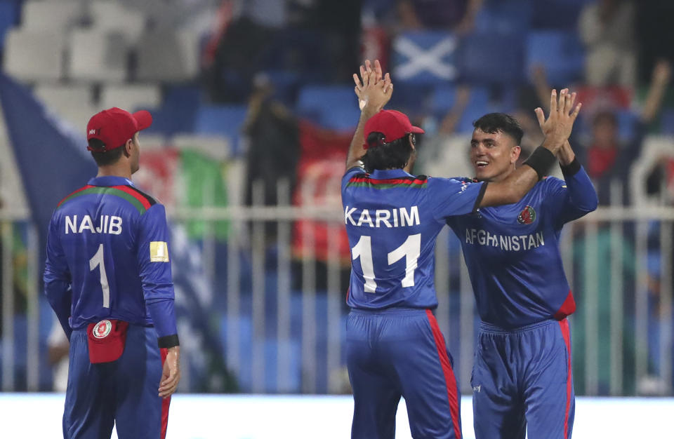 Afghanistan's Mujeeb Ur Rahman, right, celebrates the dismissal of Scotland's Calum MacLeod during the Cricket Twenty20 World Cup match between Afghanistan and Scotland in Sharjah, UAE, Monday, Oct. 25, 2021. (AP Photo/Aijaz Rahi)