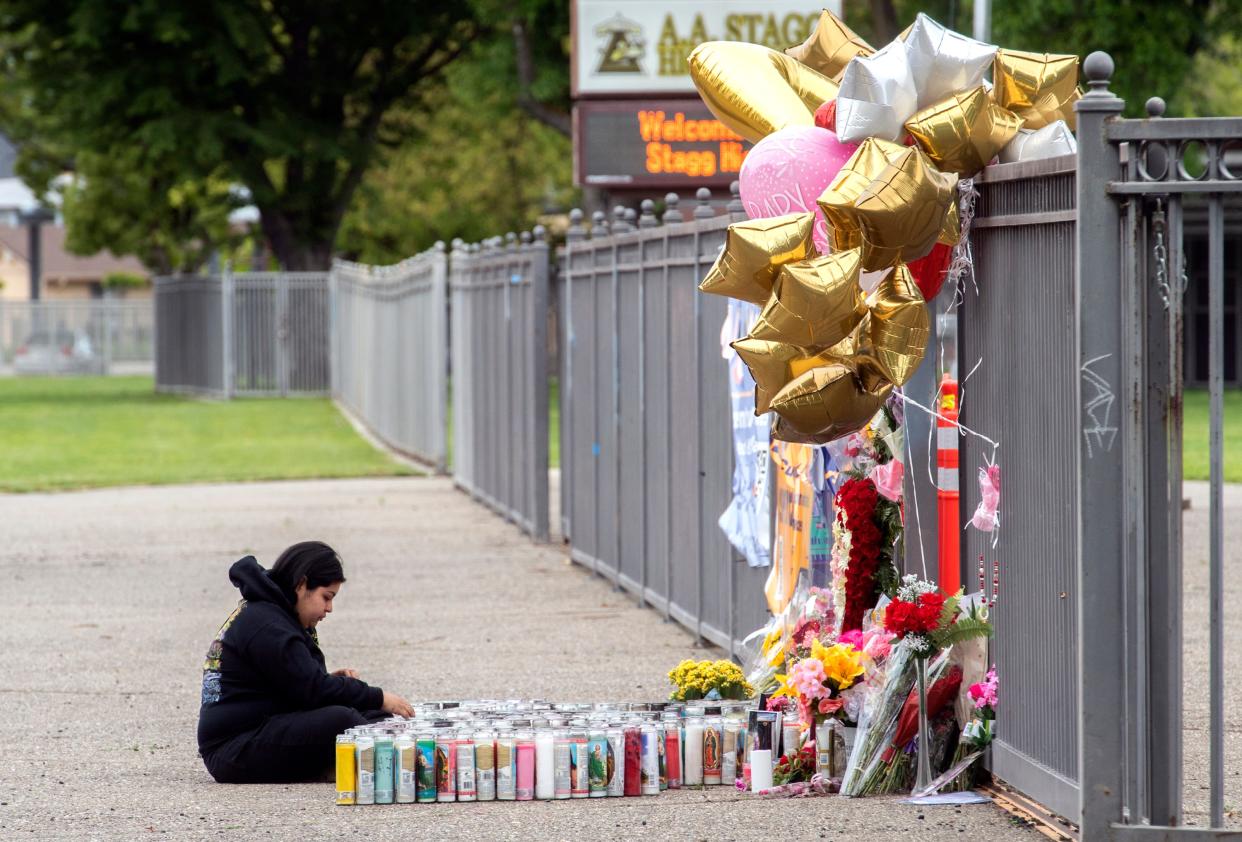 Twenty-five-year-old Miranda Garcia, who describes herself as a family friend, sits near a makeshift memorial outside the fence at Stagg High School, where 15-year-old student Alycia Reynaga was stabbed to death by an intruder at the school on April 18, 2022.