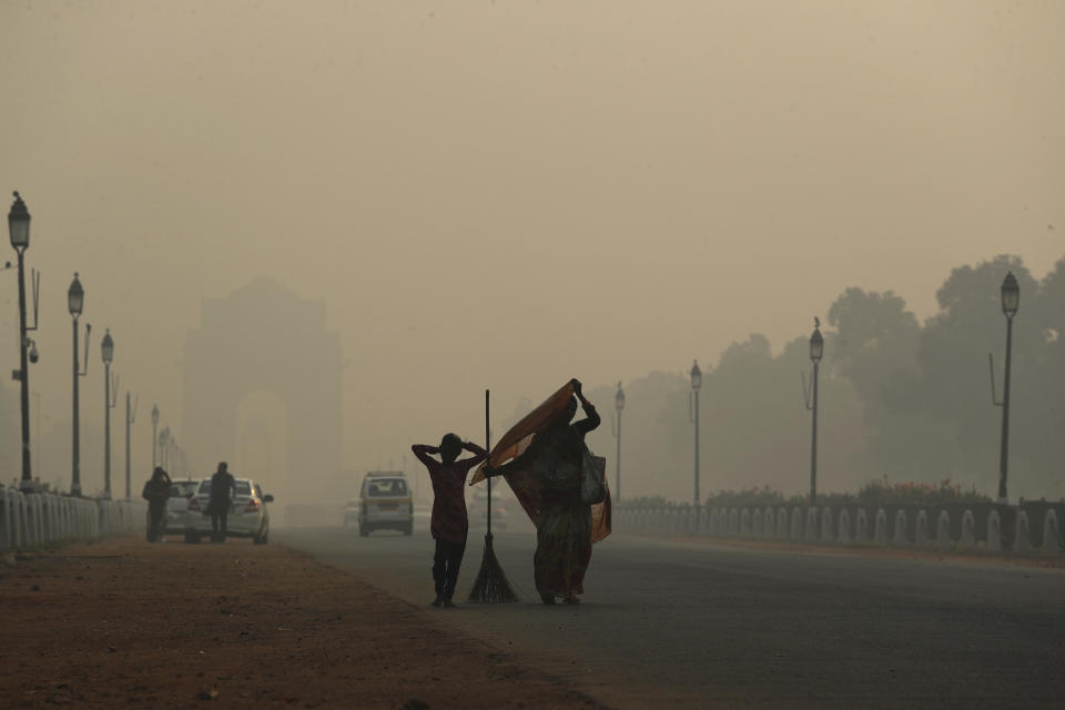 In this Thursday, Nov. 8, 2018, file photo, a municipal worker with her daughter leaves after sweeping the India Gate area as a thick lawyer of pollution haze hangs a day after Diwali festival, in New Delhi, India. Toxic smog shrouds the Indian capital as air quality falls to hazardous levels with tens of thousands of people setting off massive firecrackers to celebrate the major Hindu festival of Diwali on Wednesday night. (AP Photo/Manish Swarup, File)