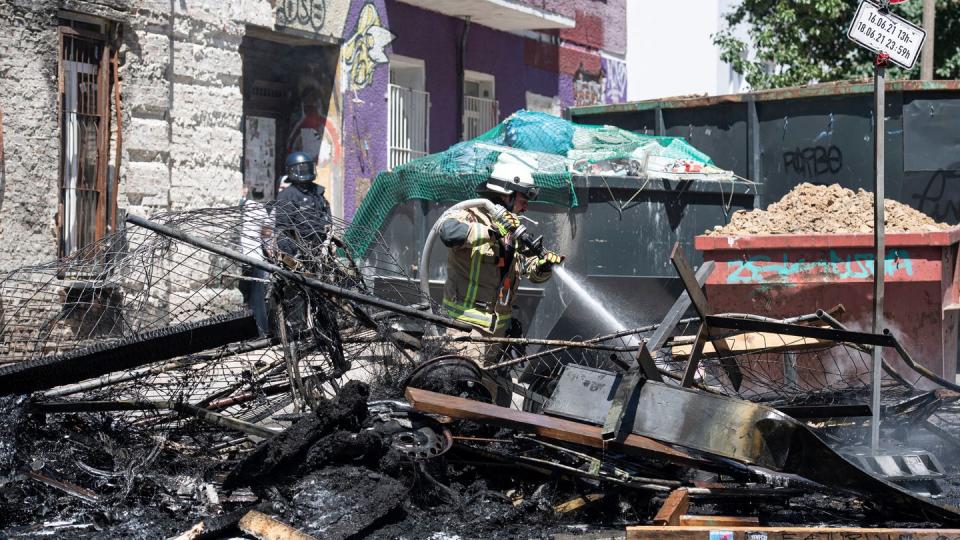 Ein Feuerwehrmann löscht eine brennende Barrikade in der Rigaer Straße in Berlin-Friedrichshain.