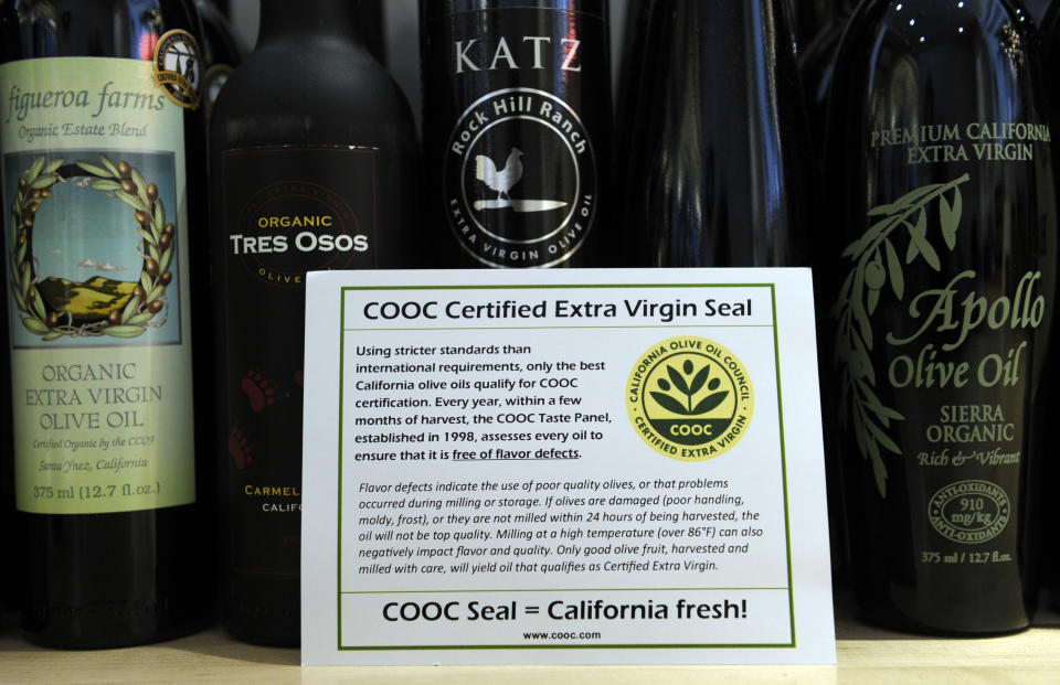 This photo taken Feb. 12, 2014 shows a card bearing a certification sticker for California olive oil displayed at the All Things Olive shop in Washington. It's a pressing matter for the tiny U.S olive oil industry. Shoppers are more often pouring European oil _ it's cheaper and viewed as more authentic than the American competition. And that's pitting U.S. producers against importers of the European oil. Some liken the battle to the California wine industry's struggles to gain acceptance decades ago. The tiny California olive industry says European olive oil filling U.S. shelves often is mislabeled and lower grade. They're pushing the federal government to give more scrutiny to imported varieties. One congressman-farmer even goes as far as suggesting labels on imported oil say "extra rancid" rather than extra virgin. Stricter standards might help American producers grab more market share from the dominant Europeans. (AP Photo/Susan Walsh)