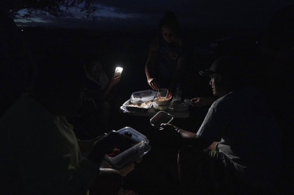 Salt makers gather for a meal after working in the Hanapepe salt patch on Sunday, July 9, 2023, in Hanapepe, Hawaii. 22 Native Hawaiian families work the beds each summer to make "paakai," or Hawaiian salt, which can only be given away or traded, never sold. (AP Photo/Jessie Wardarski)