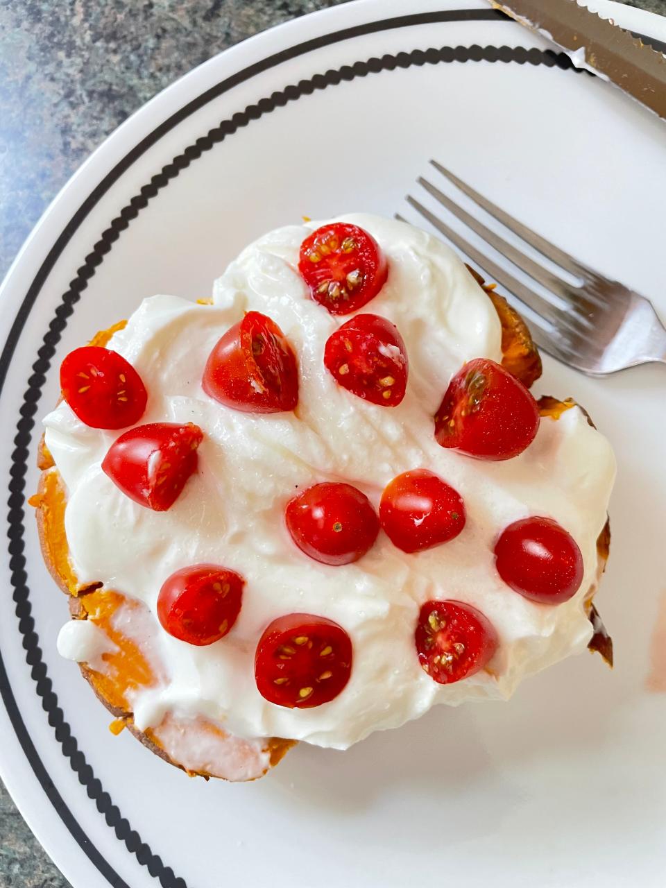Baked potatoes topped with Greek yogurt and cherry tomatoes are an easy meal option when you're not that hungry.