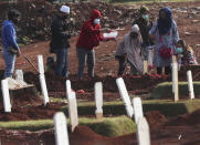 People sprinkle flowers at the grave of a family member who presumably died of COVID-19 at a cemetery in Jakarta, Indonesia Friday, June 12, 2020. As Indonesia’s virus death toll rises, the world’s most populous Muslim country finds itself at odds with protocols put in place by the government to handle the bodies of victims of the pandemic. This has led to increasing incidents of bodies being taken from hospitals, rejection of COVID-19 health and safety procedures, and what some experts say is a lack of communication from the government. (AP Photo/Achmad Ibrahim)