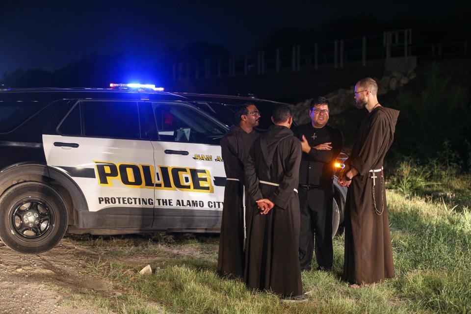 Catholic monks speak to San Antonio police officers on Monday night, asking to pray for the immigrants who died Monday in an abandoned trailer in southwestern San Antonio.