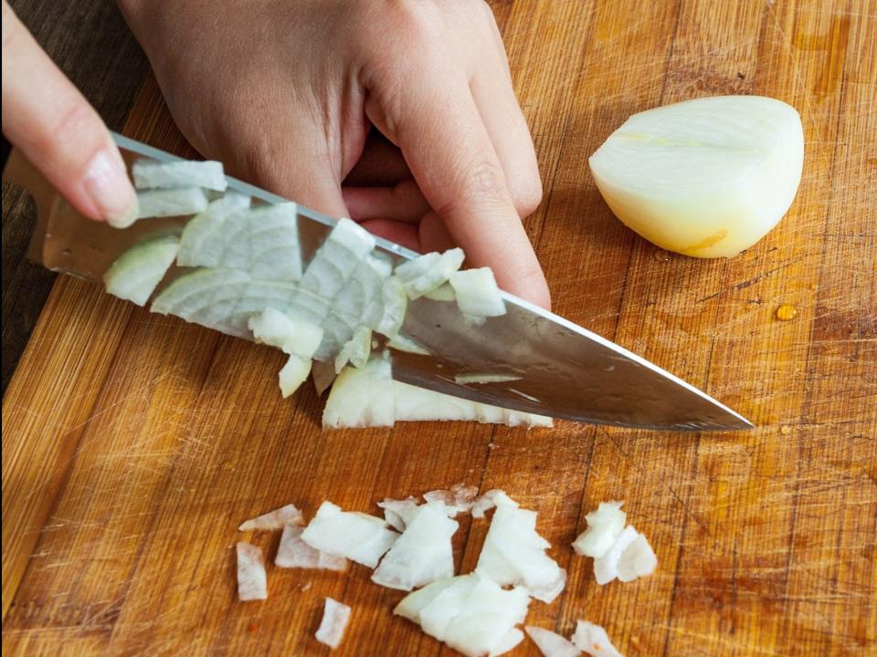 person chopping onions on a wood cutting board