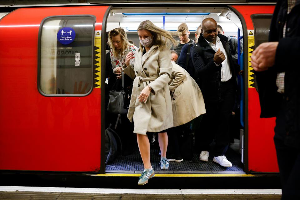 <p>Commuters, some wearing face coverings to help prevent the spread of coronavirus, walk out of a Transport for London (TfL) underground train in London on October 20, 2021. - Healthcare leaders urged the British government to reinstate some coronavirus restrictions to ease pressures on hospitals because of spiralling case numbers. But ministers remain opposed to reintroducing any curbs, arguing the situation is still far better than earlier this year and the country is learning to "live with the virus". (Photo by Tolga Akmen / AFP) (Photo by TOLGA AKMEN/AFP via Getty Images)</p>
