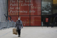 A mask-wearing woman walks in front of the New York Public Library for the Performing Arts at Lincoln Center, Thursday, March 12, 2020, in New York. Most of Lincoln Center's performance space including the Metropolitan Opera, shuttered their doors Thursday after New York Gov. Andrew Cuomo temporarily banned gatherings of more than 500 people amid a rise in cases of coronavirus. For most people the new virus causes only mild or moderate symptoms, such as fever and cough. For some, especially older adults and people with existing health problems, it can cause more severe illness including pneumonia. (AP Photo/Kathy Willens)