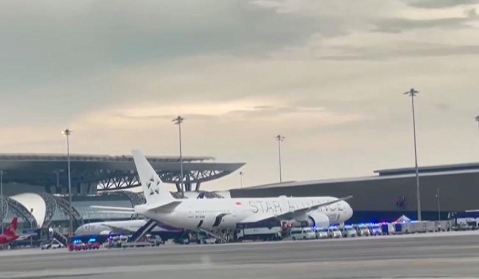 An image taken from video shows a Singapore Airlines Boeing 777-300ER sitting on the tarmac at Bangkok's                  Suvarnabhumi Airport surrounded by emergency vehicles on May 21, 2024, after flight SQ321 from London to Singapore was diverted after encountering severe turbulence. / Credit: Pongsakornr Rodphai via Reuters