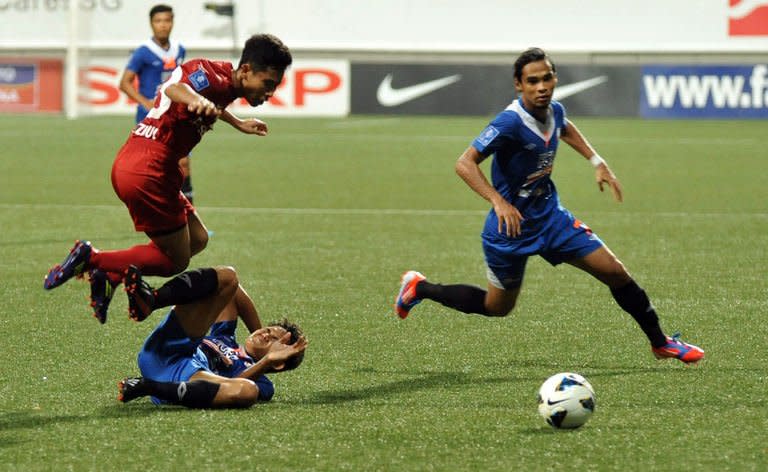 Singapore's LionsXII player Nazrul Nazari (L) leaps over KL Felda United player Mohd Akmal at the Jalan Besar Stadium during the Malaysian Super League in Singapore on July, 2 2013. The LionsXII clinched the Malaysian Super League title Tuesday with a clinical 4-0 win over minnows Felda United, rekindling the city-state's glory days in the competition after a nearly two-decade absence