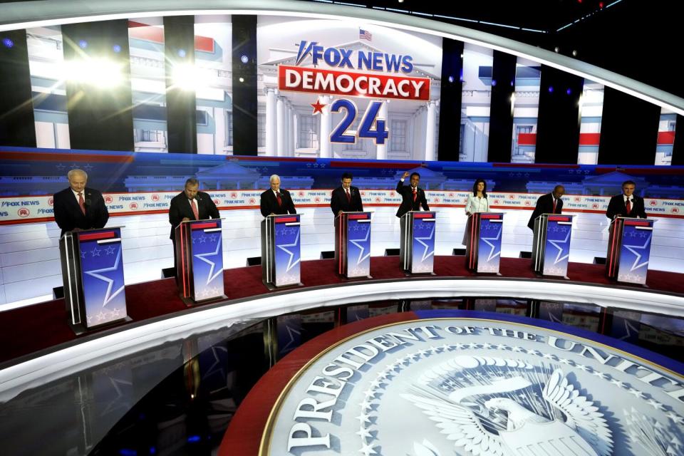 People stand behind lecterns on a stage.