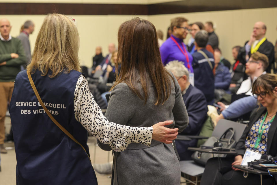 An aide guides victims to their seats during the start of the trial for the Brussels attacks, that took place on March 22, 2016, at the Justitia building in Brussels, Monday, Dec. 5, 2022. More than six years later, ten defendants face charges including murder, attempted murder and membership, or participation in the acts of a terrorist group, over the morning rush hour attacks at Belgium's main airport and on the central commuter line on March, 22, 2016. (AP Photo/Olivier Matthys, Pool)