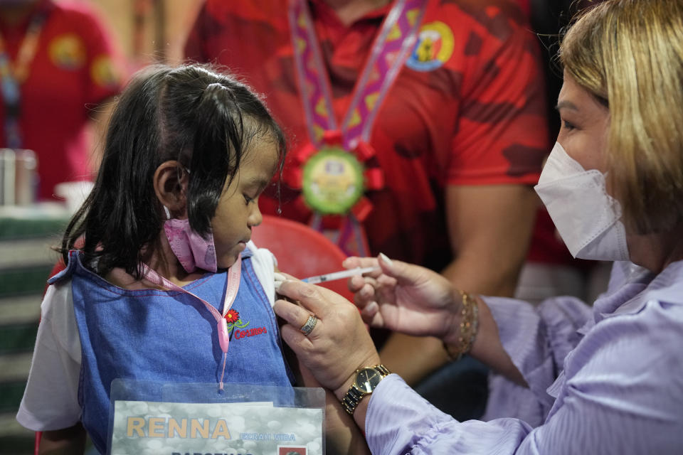 A girl receives her first COVID-19 Pfizer vaccination during the opening of classes at the San Juan Elementary School in metro Manila, Philippines on Monday, Aug. 22, 2022. Millions of students wearing face masks streamed back to grade and high schools across the Philippines Monday in their first in-person classes after two years of coronavirus lockdowns that are feared to have worsened one of the world's most alarming illiteracy rates among children. (AP Photo/Aaron Favila)