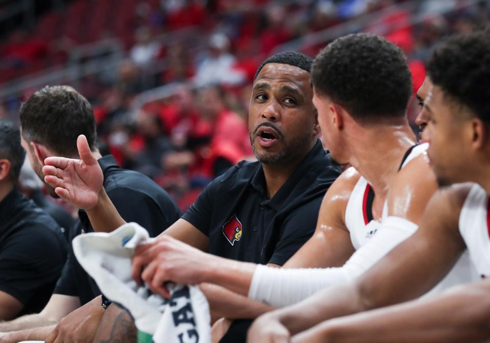 U of L assistant coach Mike Pegues, center, instructs Samuell Williamson (10) on the bench against West Georgia during their game at the Yum Center in Louisville, Ky. on Nov. 3, 2021.  