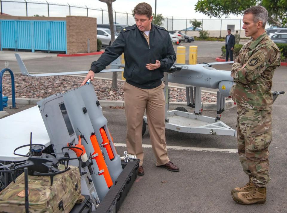 An individual assigned to Naval Special Warfare Command, at left, shows payload modules for the RQ-21 Blackjack, including one holding a small quadcopter-type drone, to U.S. Army Gen. Richard Clarke, commander of U.S. Special Operations Command, December 13, 2021. <em>U.S. Navy</em>