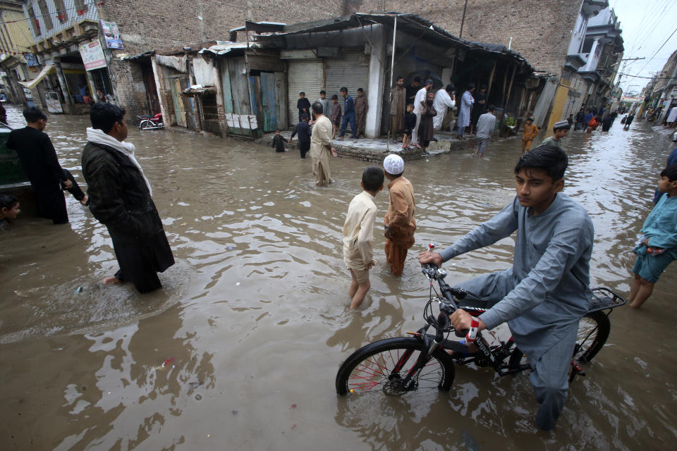 Youngsters wade through a flooded street caused by heavy rain in Peshawar, Pakistan, Monday, April 15, 2024. Lightening and heavy rains killed dozens of people, mostly farmers, across Pakistan in the past three days, officials said Monday, as authorities declared a state of emergency in the country's southwest following an overnight rainfall to avoid any further casualties and damages. (AP Photo/Muhammad Sajjad)