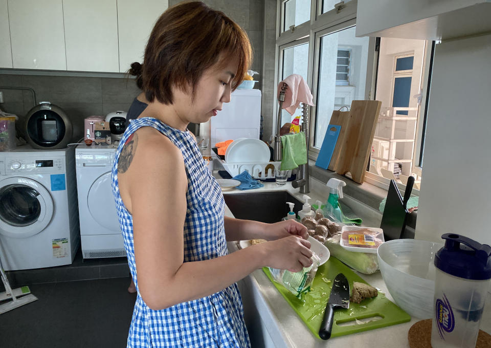 Chan Jit Yen prepares ingredients for a Lunar New Year hot pot lunch she is hosting for Malaysian students at her rented apartment in Singapore Saturday, Feb. 13, 2021. With Malaysian workers and students stranded in the city state over the Lunar New Year due to coronavirus travel restrictions, the Malaysian Association in Singapore has called on Malaysians to treat students to a meal. (AP Photo/Annabelle Liang)