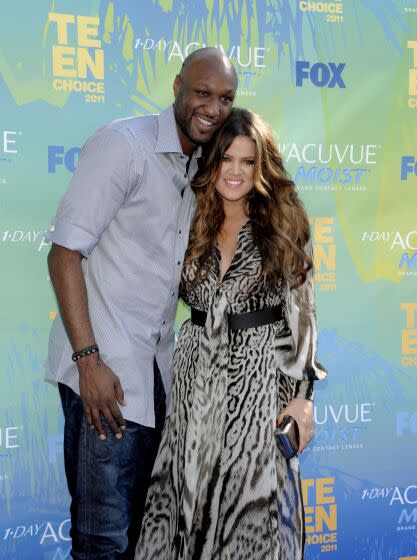 Lamar Odom in a grey button down shirt and Khloe Kardashian in an animal print dress