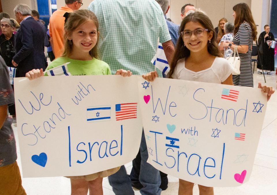 Emmaline Morris, left, and Kassidie Snyder hold homemade signs Wednesday night at the "Stand for Israel" rally held at Temple Emanuel in Lakeland. About 300 people attended the gathering.