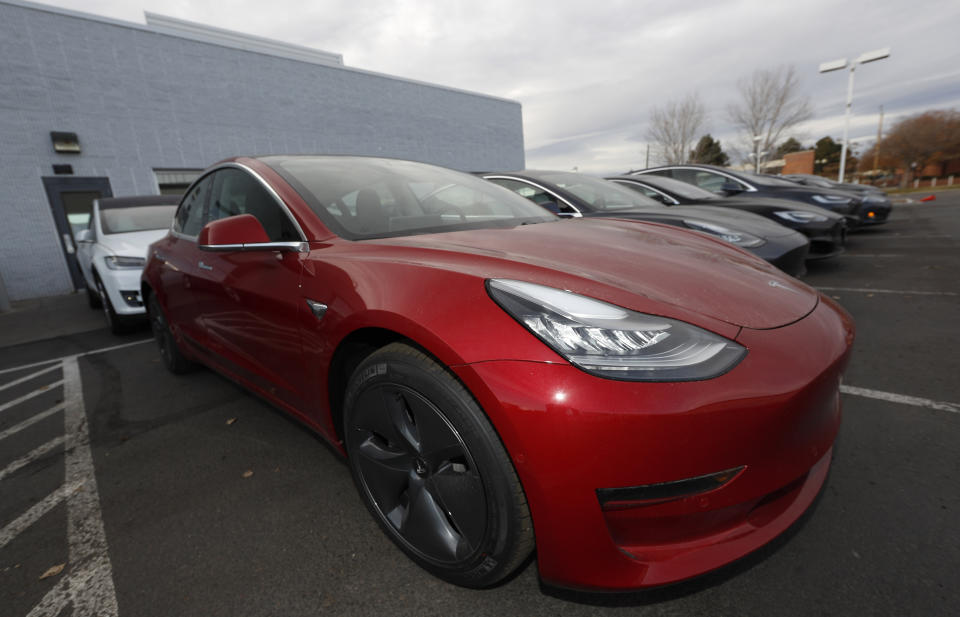 In this Sunday, Nov. 10, 2019, photograph, a long row of unsold 2020 Model 3 sedans sits at a Tesla dealership in Littleton, Colo. (AP Photo/David Zalubowski)