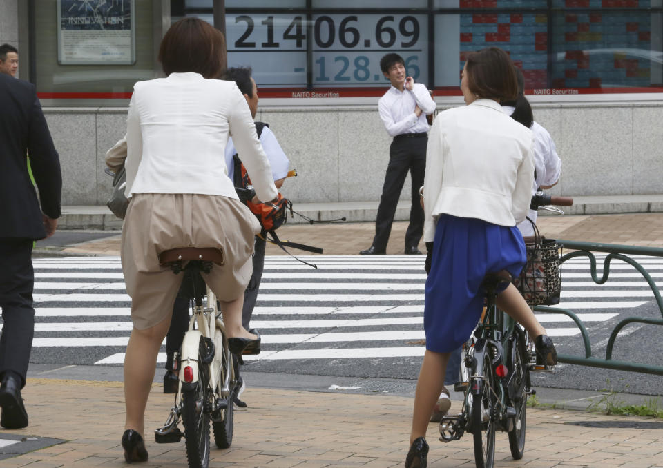 People wait to cross a street near an electronic stock board of a securities firm in Tokyo, Wednesday, July 17, 2019. Asian stocks were mixed Wednesday as Wall Street ended a five-day winning streak after the first big round of corporate earnings reports. (AP Photo/Koji Sasahara)