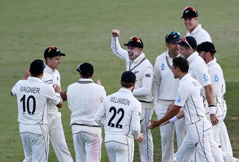 Mitchell Santner, second left, is surrounded by teammates after dismissing Pakistan captain Mohammad Rizwan with a direct throw during play on day three of the first cricket test between Pakistan and New Zealand at Bay Oval, Mount Maunganui, New Zealand, Monday, Dec. 28, 2020. (Andrew Cornaga/Photosport via AP)