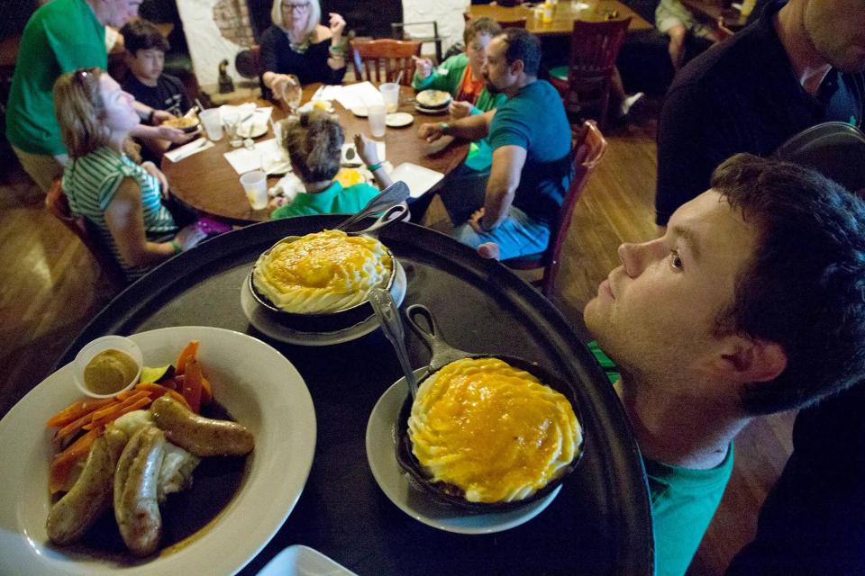 A server delivers bangers and mash and shepherd's pie orders to a table at Paddy Mac's on St. Patrick's Day in 2018.