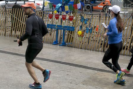 Two runners pass by a memorial for the victims of the 2013 bombing attack near the Boston Marathon finish line in Boston, Massachusetts, April 17, 2015. REUTERS/Dominick Reuter