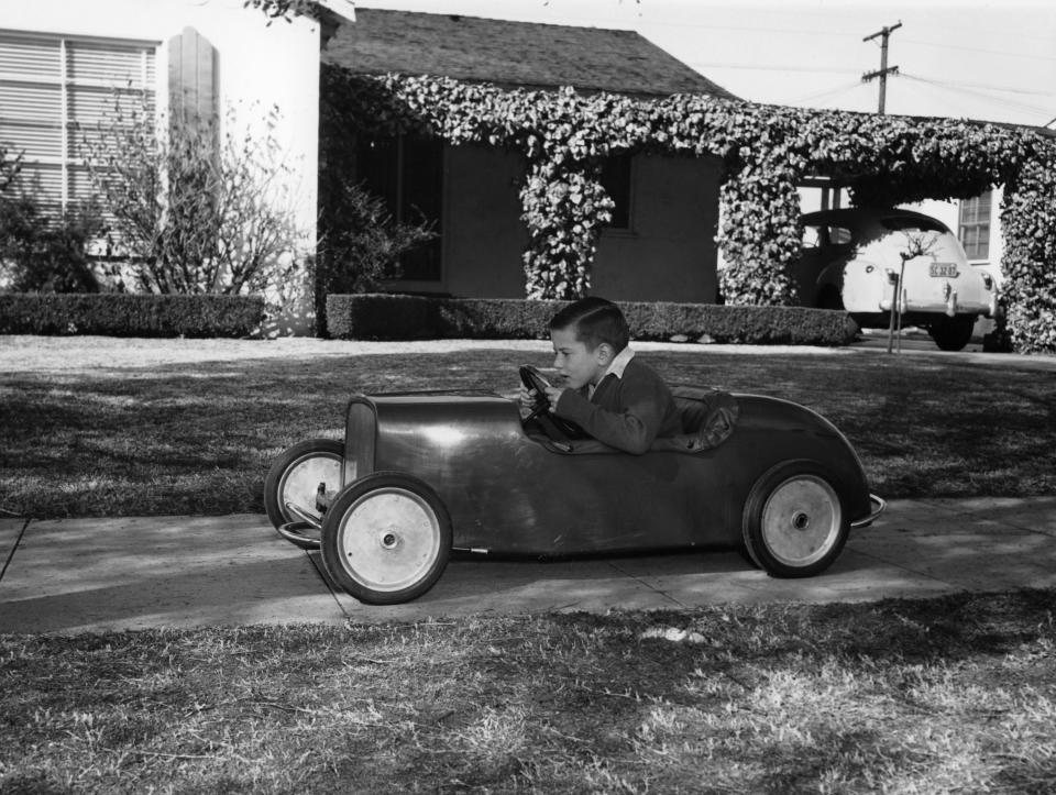 Circa 1953: Boy in a pedal car. Driving his pedal car on the pavement outside his house. (Photo by National Motor Museum/Heritage Images/Getty Images)