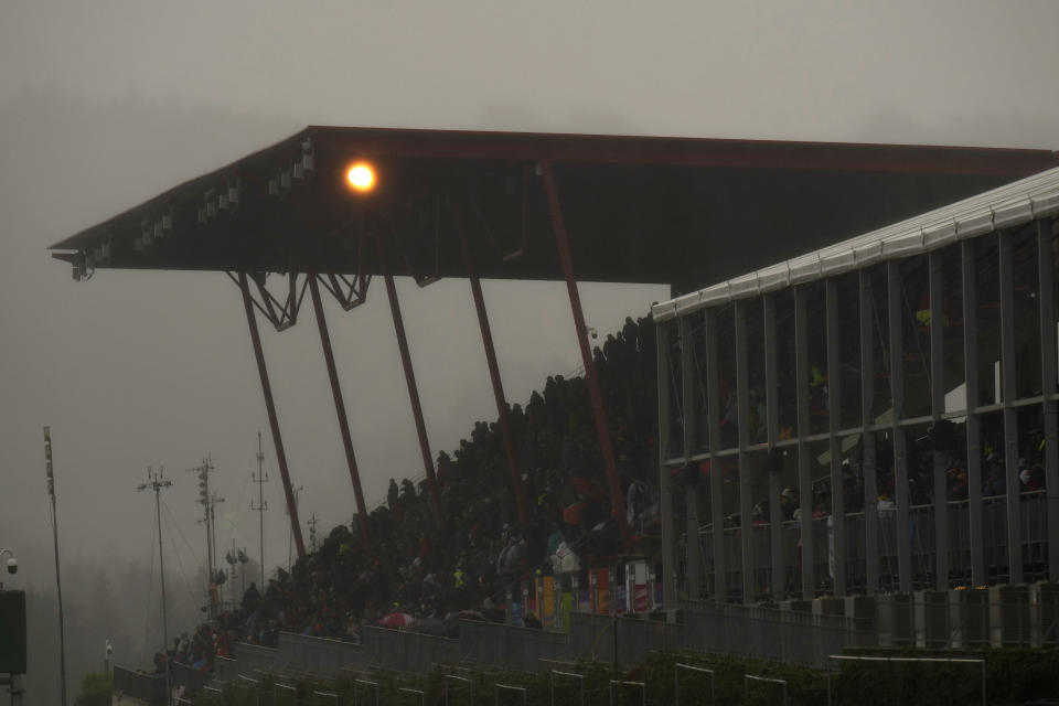 Spectators wait under an overhang during a rain delay at the Formula One Grand Prix at the Spa-Francorchamps racetrack in Spa, Belgium, Sunday, Aug. 29, 2021. (AP Photo/Francisco Seco)