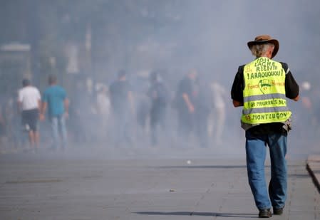 A protester wearing a yellow vest walks among tear gas as protesters clash with French riot police during a demonstration on Act 44 (the 44th consecutive national protest on Saturday) of the yellow vests movement in Nantes