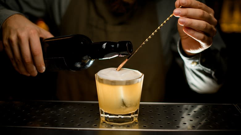 Bartender pouring foam onto cocktail