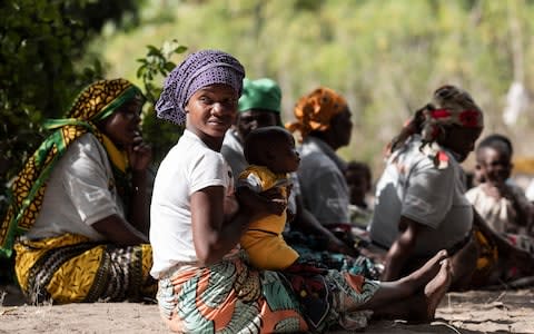 A woman looks on as she holds her baby at Namissica village during a fair/community-based provision of FP services through a mobile clinic near Nacala Porto on July 04 2018 in Namissica, Nampula Province, Mozambique - Credit: Xaume Olleros 