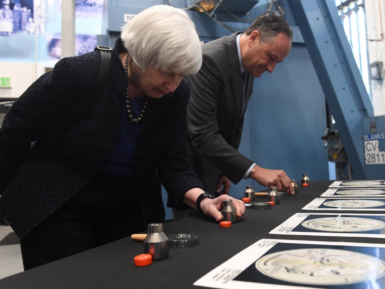 US Secretary of the Treasury Janet Yellen and Second Gentleman Douglas Emhoff standing at a table while inspecting a series of dies at the Denver Mint.