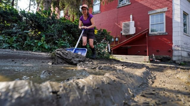 A volunteer cleans mud off sidewalks in Vermont