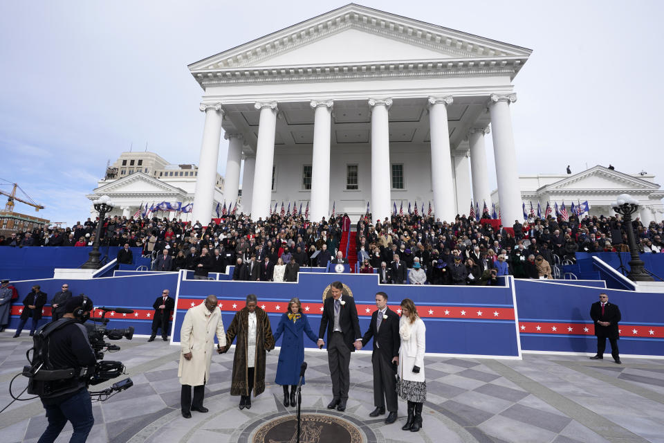 Virginia Gov. Glenn Youngkin, third from right, and his wife, Suzanne, third from left, offer a prayer along with Attorney General Jason Miyares, second from right, his wife, Page, as well as Lt. gov. Winsome Earle-Sears, second from left and her husband, Terence, left, join in at the Capitol Saturday Jan. 15, 2022, in Richmond, Va. (AP Photo/Steve Helber)