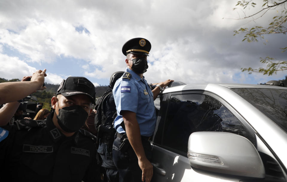 Police guard a vehicle in which former Honduran President Juan Orlando Hernandez is being transported to the Police Headquarters to be shown to the press, in Tegucigalpa, Honduras, Tuesday, Feb. 15, 2022. Police arrested Hernandez at his home, following a request by the United States government for his extradition on drug trafficking and weapons charges. (AP Photo/ Elmer Martinez)