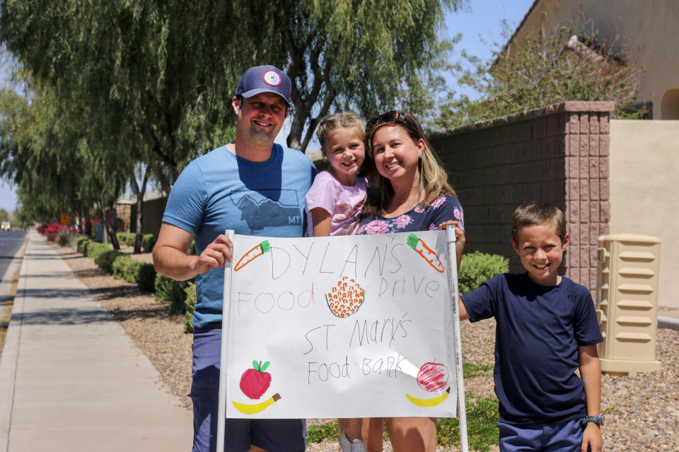 Nick, Evelyn, Erin and Dylan Pfeifer stand together near their home in Chandler, Ariz., holding a hand-drawn sign promoting a food drive on Saturday, April 3, 2021. Dylan Pfeifer hosted his third food drive since October in response to the coronavirus pandemic. “It’s been hard to interact with people, especially now, so this provides a safe way to do that. I just wanted to provide him a way to make an impact,” Erin Pfeifer said. (AP Photo/Cheyanne Mumphrey)