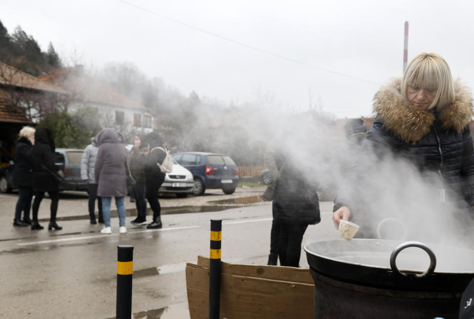 A woman prepares refreshments for people on the road by a barricade near the village of Rudare, north of Serb-dominated part of ethnically divided town of Mitrovica, Kosovo, Monday, Dec. 12, 2022. Tensions between Serbia and Kosovo flared during the past week after Serbs erected barricades on the main roads in the north of the former Serbian province to protest the arrest of a former Kosovo Serb police officer. (AP Photo/Marjan Vucetic)