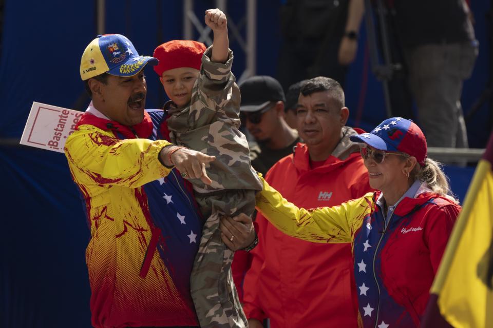 FILE - Venezuelan President Nicolas Maduro holds up a child wearing a signature red beret associated with the late President Hugo Chavez, alongside first lady Cilia Flores, during a commemorative event, in Caracas, Venezuela, Feb. 29, 2024. Maduro became Venezuela's interim president in March 2013 after the death of Chávez and elected a few months later. (AP Photo/Ariana Cubillos, File)