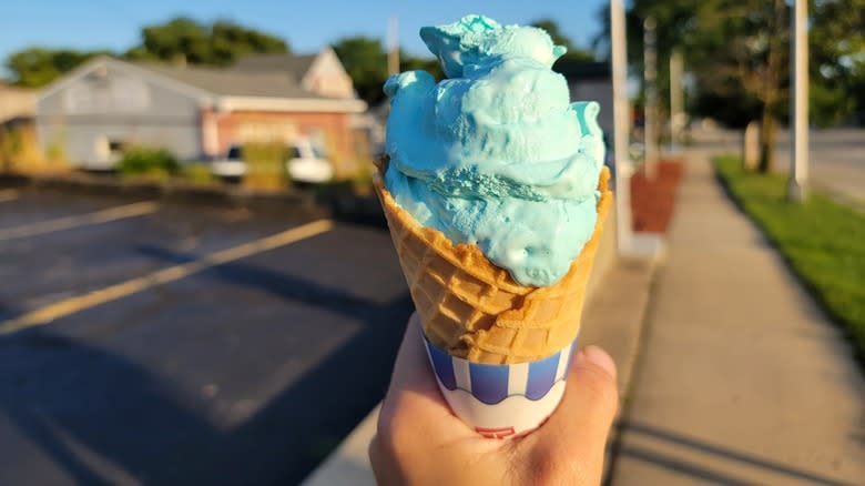 Hand holding blue moon ice cream in a waffle cone