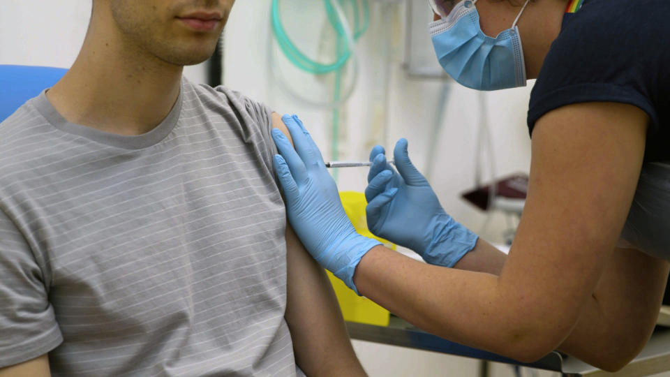 A volunteer at Britain's Oxford University is injected with either an experimental COVID-19 vaccine or a comparison shot as part of the first human trials in the UK.