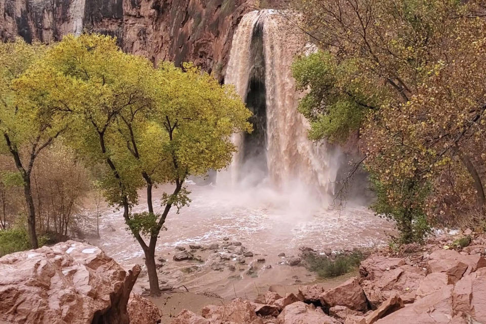 This Nov. 29, 2019, photo, shows a normally blue-green waterfall in Supai, Arizona, that turned chocolate brown after flooding. A popular tourist spot deep in a gorge off the Grand Canyon was flooded over the holiday, sending tourists scrambling to higher ground. The flood happened just days before the Havasupai Tribe shuts down its reservation to tourists for the season. No one was injured but some tourists woke up drenched and some lost camping gear. (Mandy Augustin via AP)