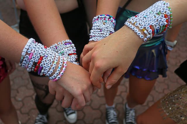 <p>Lisa Maree Williams/Getty</p> Taylor Swift fans showing off their friendship bracelets at the Eras Tour in Sydney, Australia