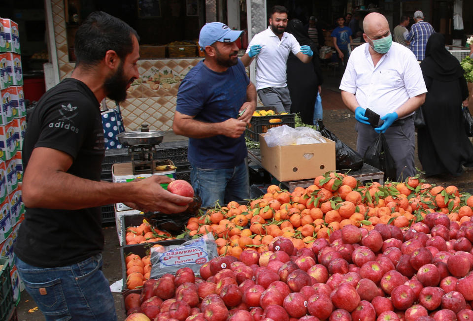 Iraqis buy groceries in downtown Baghdad, Iraq, Monday, March 16, 2020. Iraq announced a weeklong curfew late Sunday. People raced to supermarkets and swiftly emptied shelves, while others stocked up on cooking fuel. The curfew, which is set to begin late Tuesday, includes the suspension of all flights from Baghdad's international airport. (AP Photo/Khalid Mohammed)