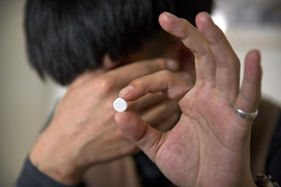 In this March 28, 2019, photo, Yin Hao, who also goes by Yin Qiang, holds a Tylox pill while sitting in a tea house in Xi'an, northwestern China's Shaanxi Province. Officially, pain pill abuse is an American problem, not a Chinese one. But people in China have fallen into opioid abuse the same way many Americans did, through a doctor's prescription. And despite China's strict regulations, online trafficking networks, which facilitated the spread of opioids in the U.S., also exist in China. (AP Photo/Mark Schiefelbein)
