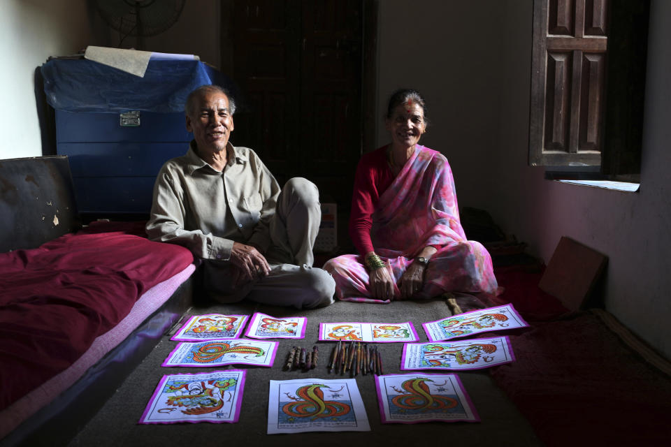 In this July 31, 2019, photo, Chitrakar couple Tej Kumari and Purna, left, pose for photographs at their residence in Bhaktapur, Nepal. Chitrakar families in the Nepalese capital of Kathmandu were renowned traditional painters and sculptors who depicted gods and goddesses on temples, masks of Hindu deities and posters for various religious celebrations. For the Chitrakar couple it is a struggle to keep the dying art alive against the modern mass produced prints. (AP Photo/Niranjan Shrestha)